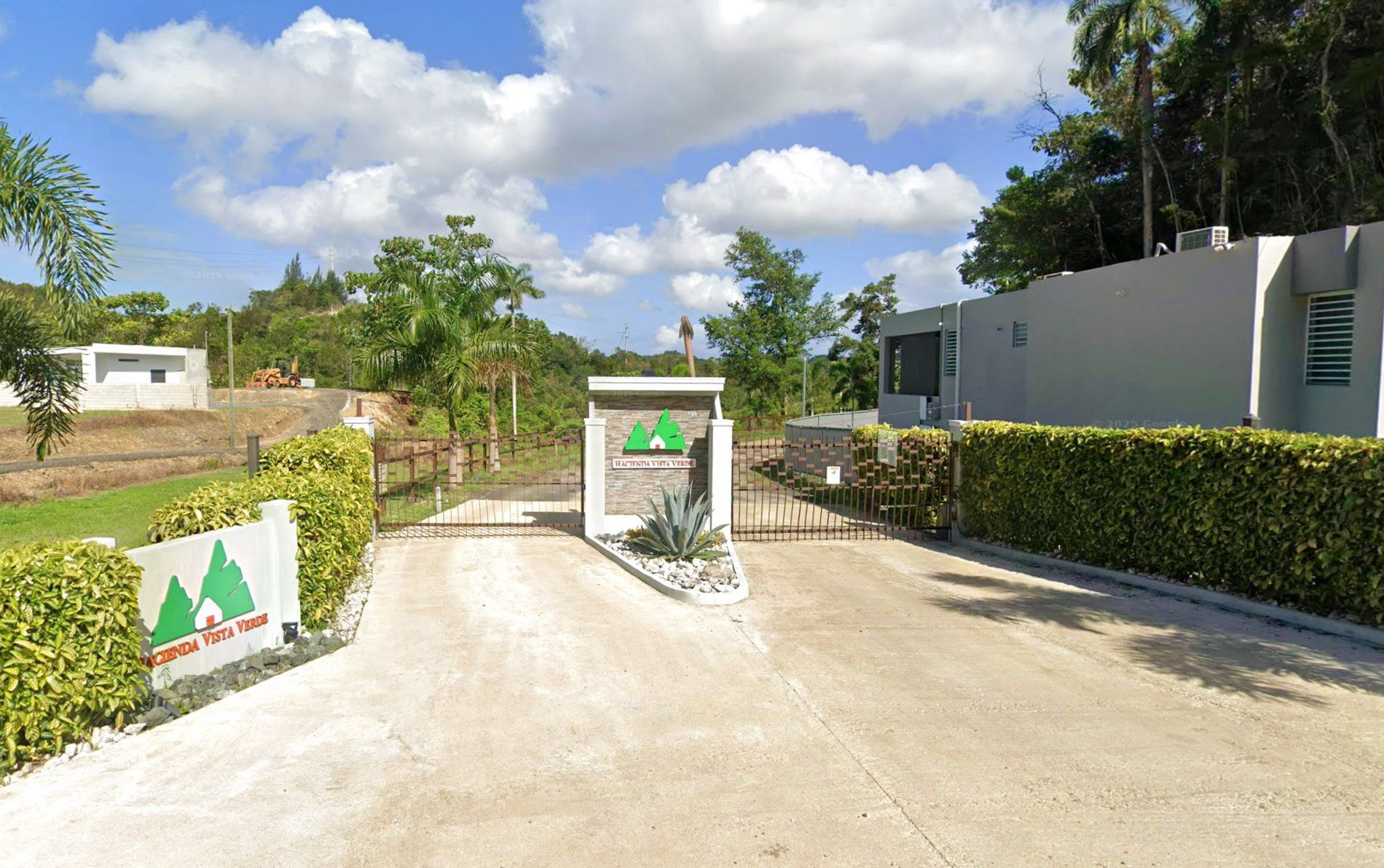 Entrada de Hacienda Vista Verde con portón, rótulo y verjas de arbustos